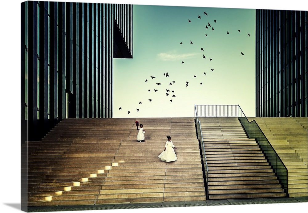 Two girls in white dresses on a staircase in La Defense, Paris, chasing birds.