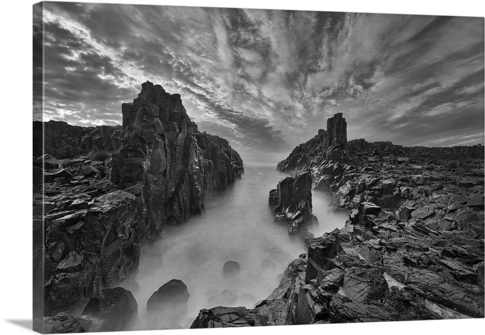 Cloudy skies over mist on the rocky coast of Bombo, New South Wales, Australia.