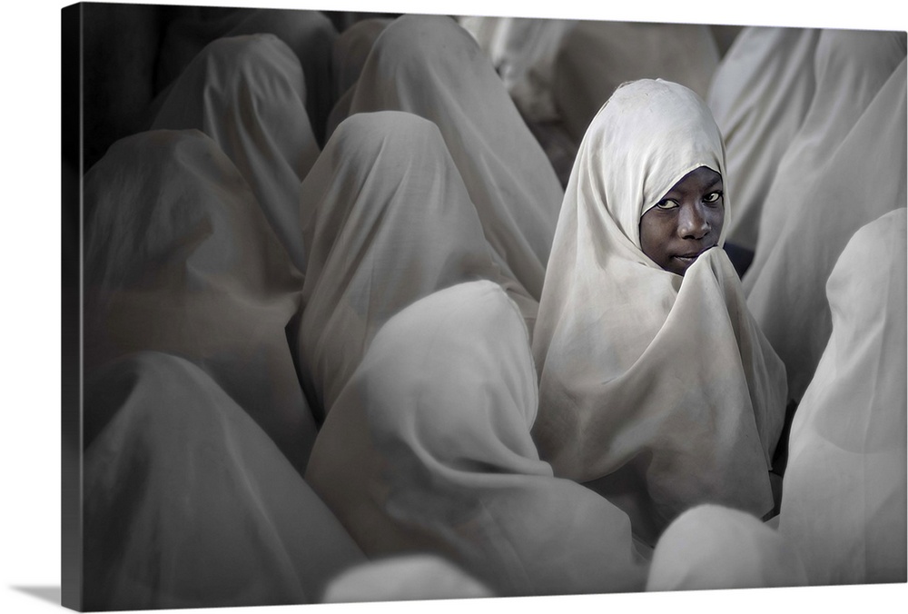 A young girl in Tanzania turns around, among other women wearing veils.
