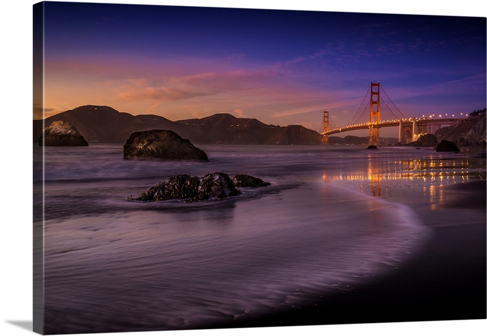 Lights on the Golden Gate Bridge in San Francisco seen from the beach at twilight.