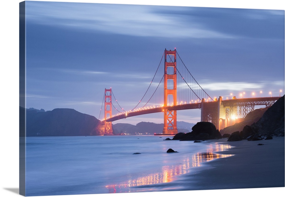 A soft and dreamy photograph of the golden gate bridge in San Francisco lit up in the early evening