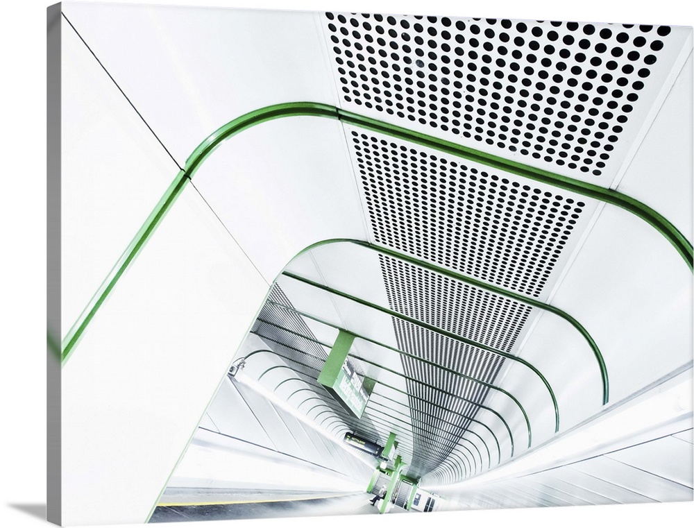 Abstract view of a stark white tunnel in a train station lined with bright green lines.