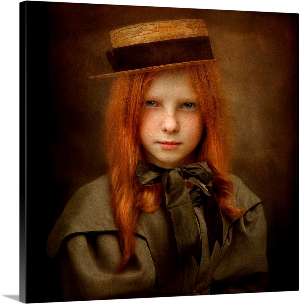 A child with long red hair wearing a straw hat and a ribbon tied in a bow.