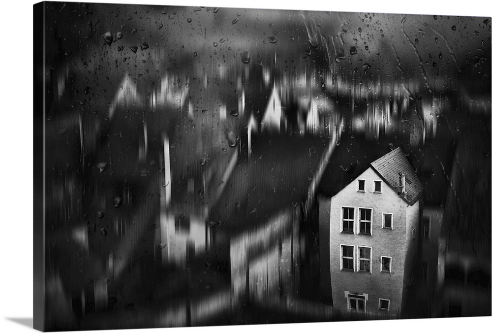 View through a window with raindrops of a blurred village scene, with one house in focus.