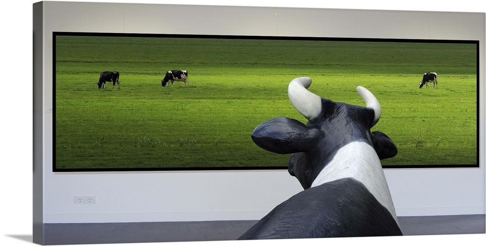 Conceptual image of a cow looking at a framed photo of other cows in a green field.