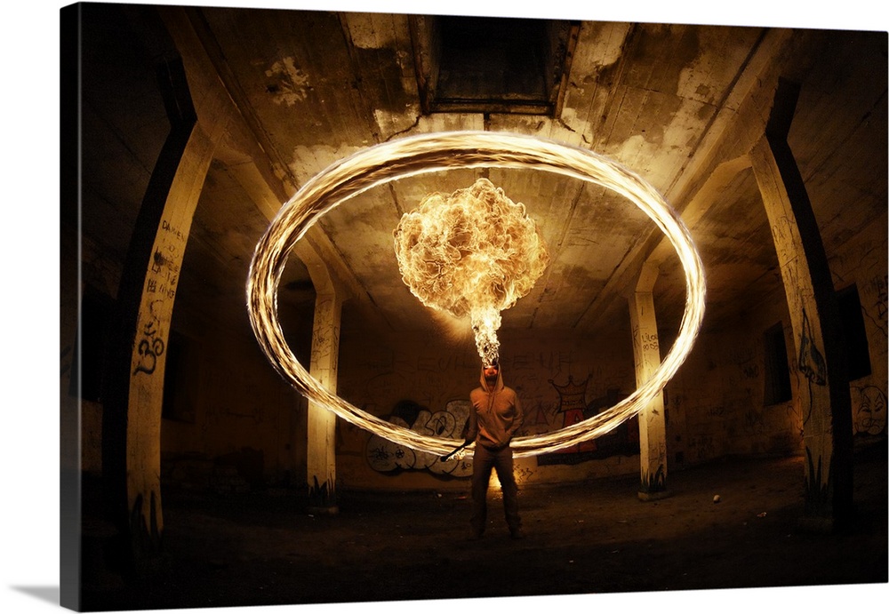 A man appears to breathe fire wit ha ring of light in the air around him, in a concrete structure.
