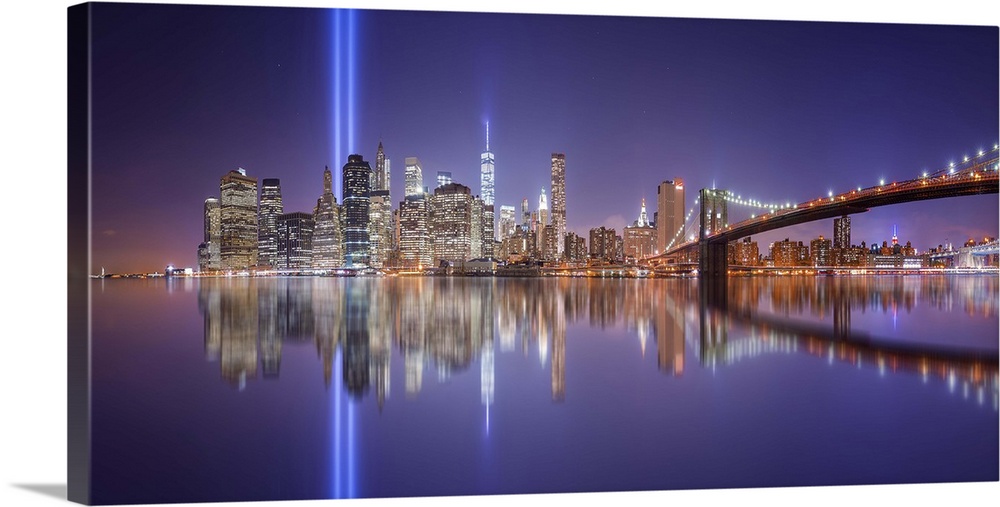 A dynamic photograph of the NYC skyline with the Twin Towers memorial lights shining brightly.