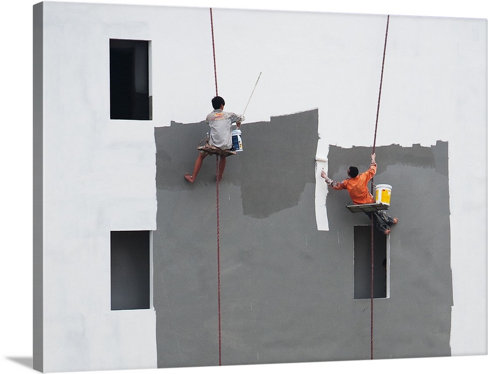 Two painters working on a building, hanging from ropes in Hanoi, Vietnam.