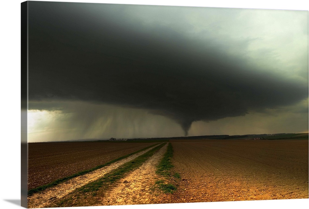 A tornado extends into the horizon from storm-clouds overhead, seen from across farmland.