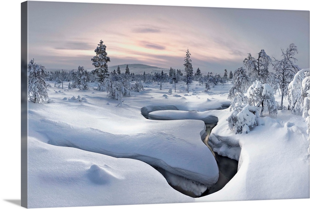 A river cuts a curved path through a landscape with a think blanket of snow in Finland.