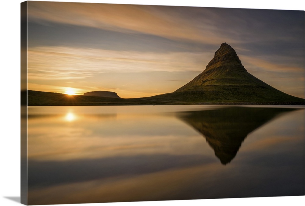 Kirkjufell mountain at sunrise, reflected in the calm water below, Iceland.