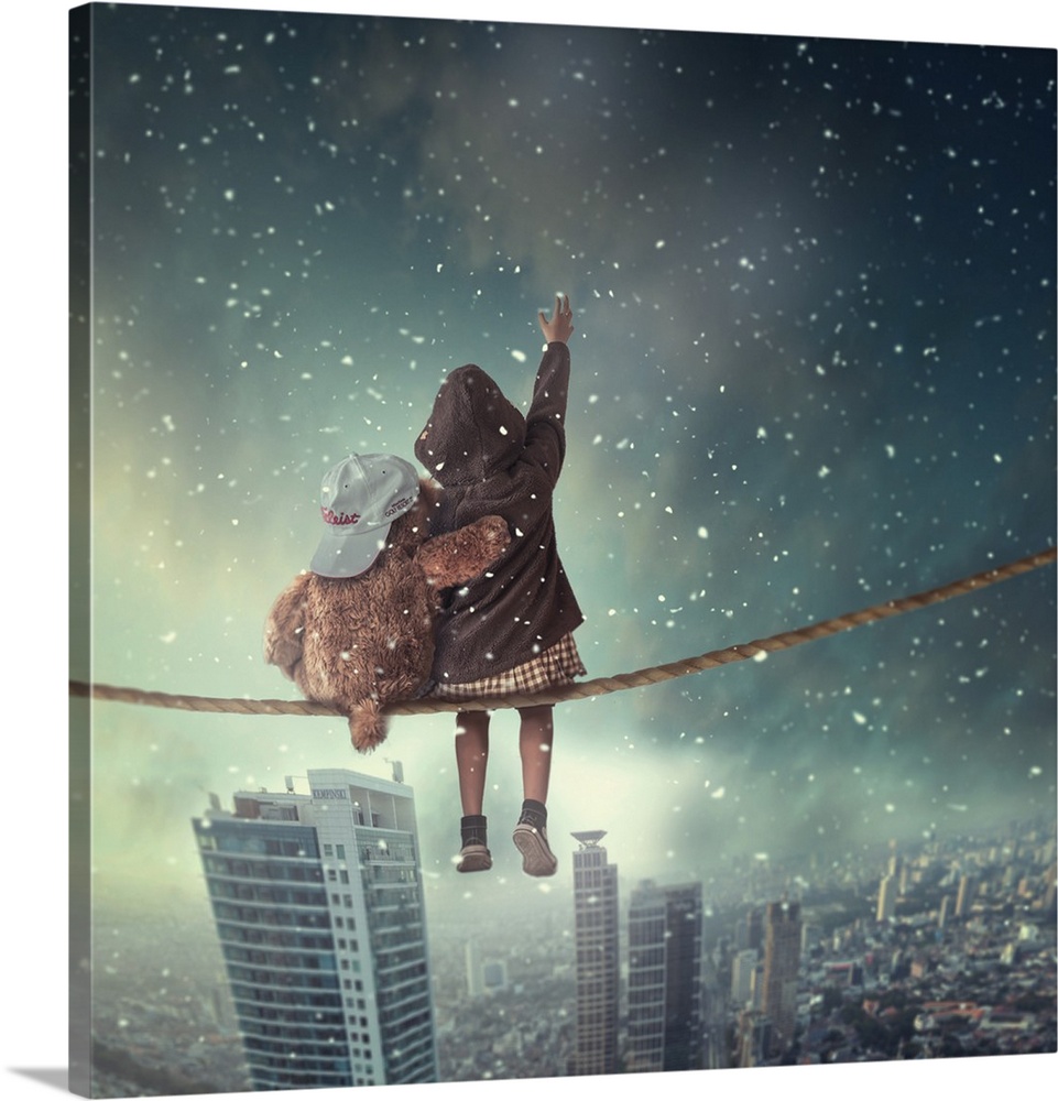 Surreal image of a child and a teddy bear sitting on a cable overlooking a city as snow falls.