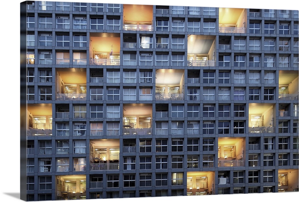 The side of a building filled with windows, and a repeating pattern of lit balconies.