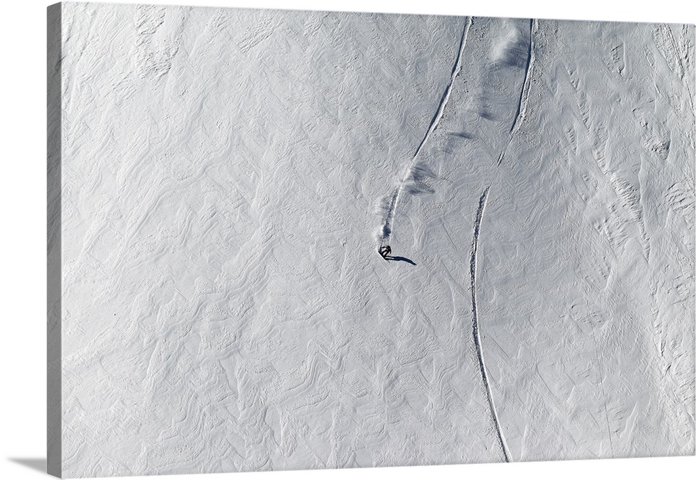 Aerial view of a snowboarder cruising down a snowy mountain.