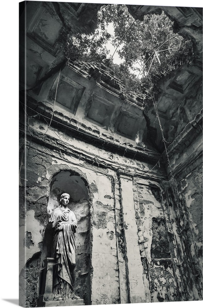 Blue toned black and white photograph of the interior of an old building highlighting a statue, a hole in the ceiling, and...