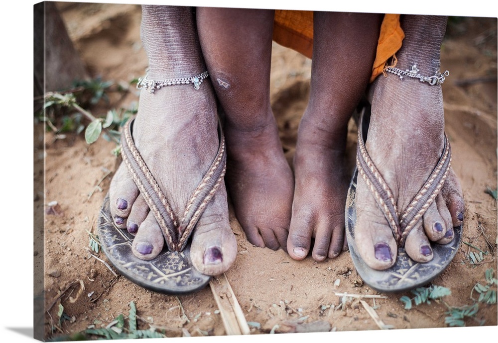 A woman's feet in sandals covered in dust, with her child's small feet between them.