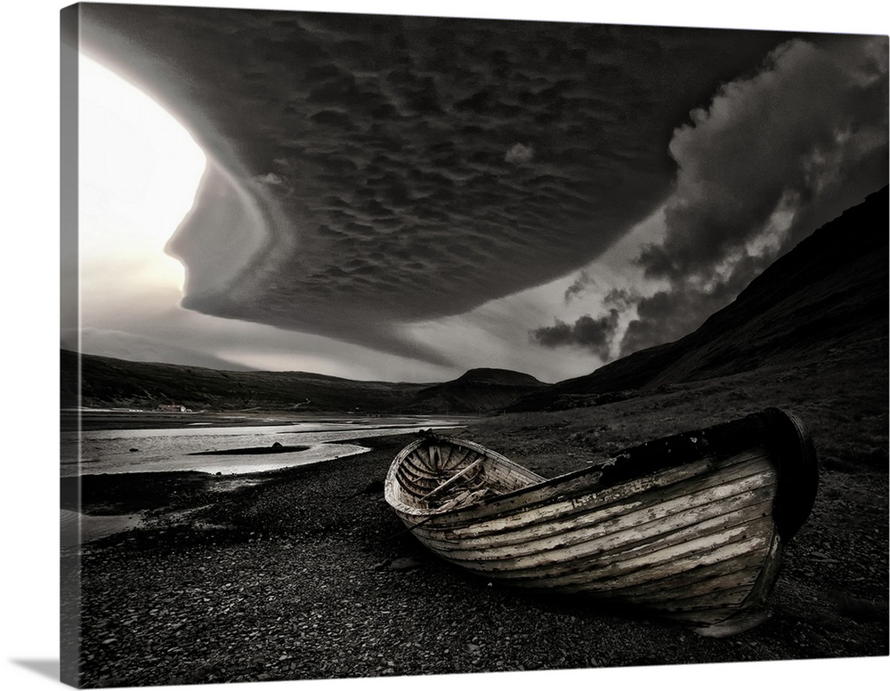 A weathered wooden boat o nthe beach under dark clouds in Iceland.