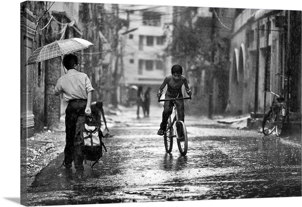 A young boy riding his bike through the streets in the rain, Bangladesh.