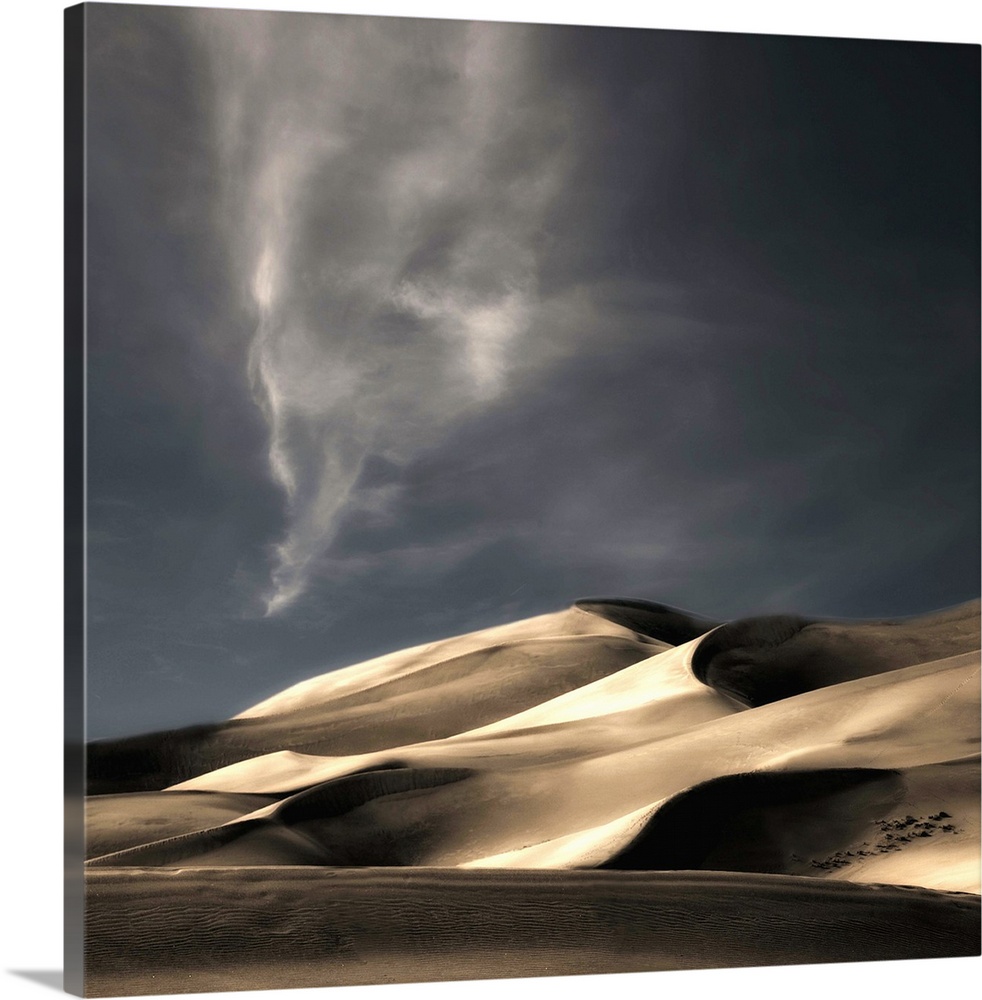 Desert sand dunes casting deep shadows under a darkening sky, Colorado.