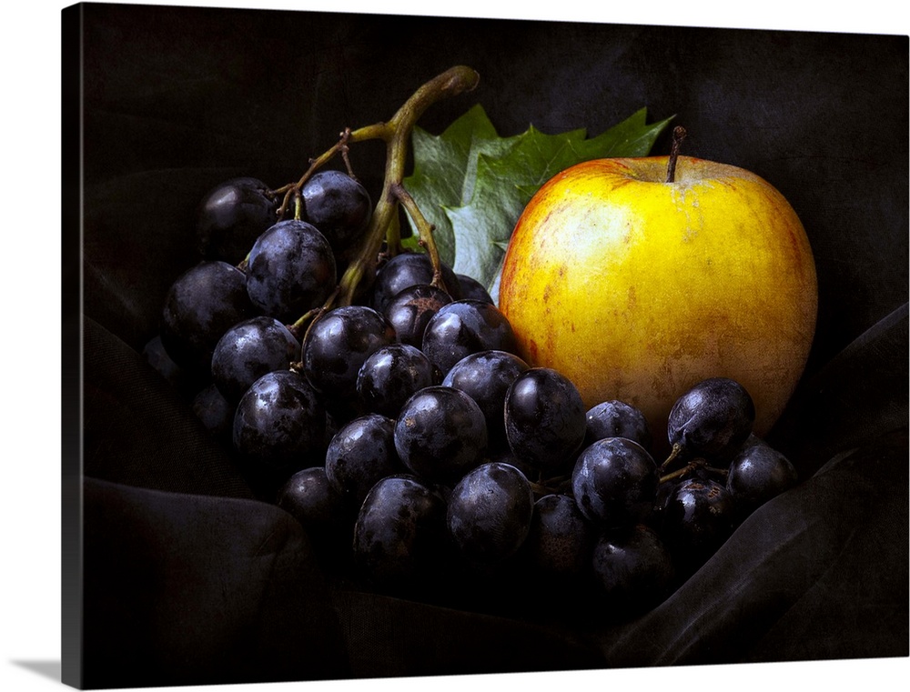 Fine art still life photo of bunch of dark red grapes and a golden apple.