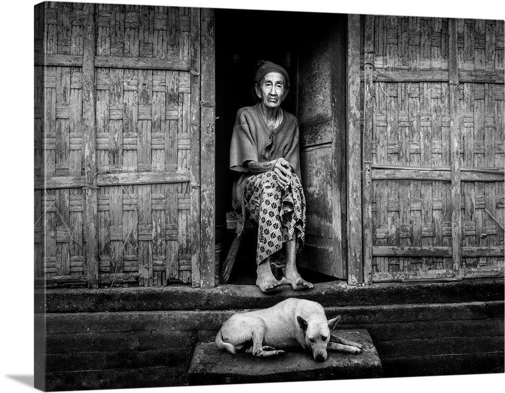 An elderly woman sitting in her doorway with a dog at her feet, Bangli, Bali, Indonesia.