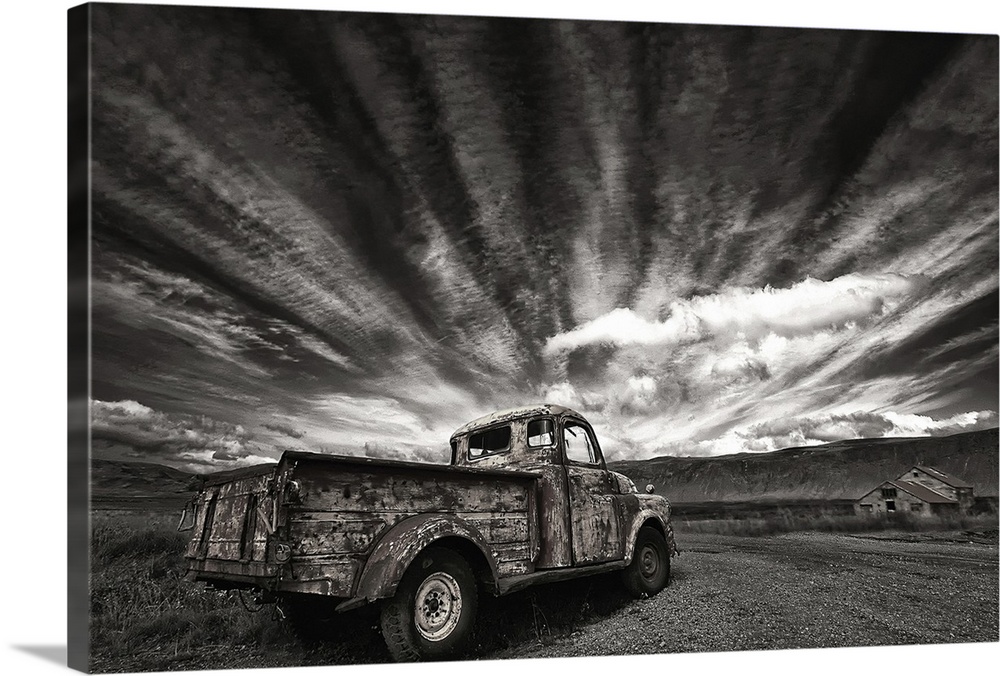 Abandoned old truck in a field under dramatic clouds, Iceland.