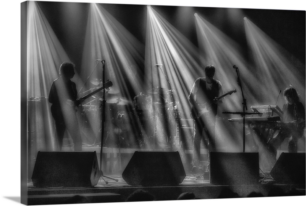 A musical group performing on a stage under streams of spotlights.