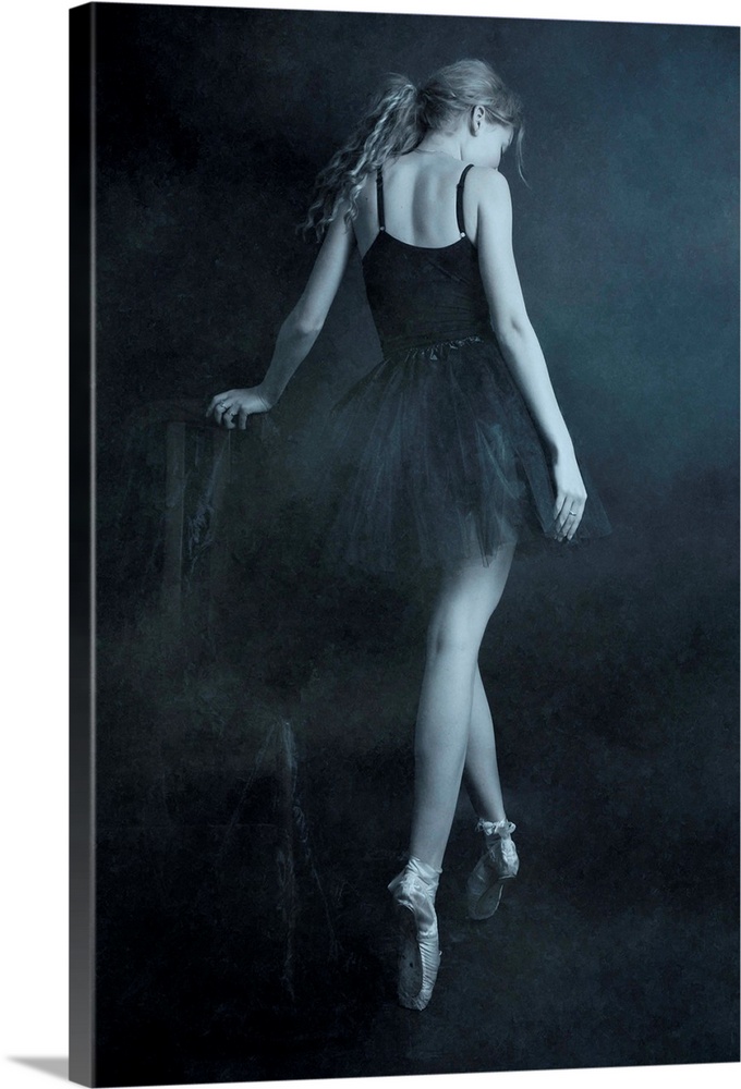 A ballerina in a black dress standing on her toes, with her back turned.