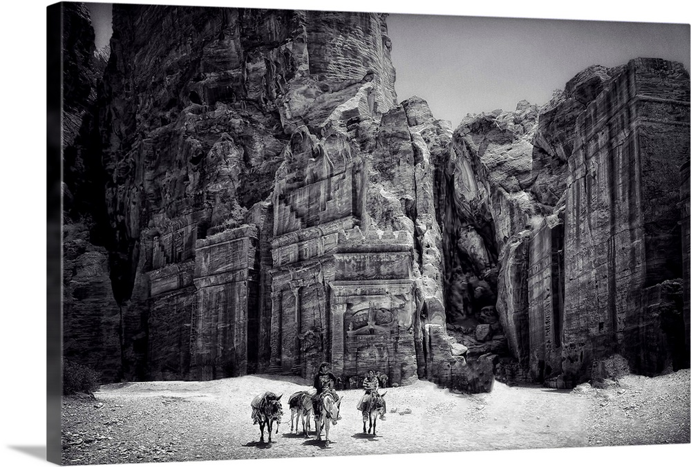 People with donkeys in front of the temple at Petra, Jordan, in the desert.