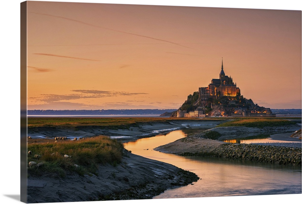 Warm landscape photograph of rivers leading to a castle on top of a hill at sunset.