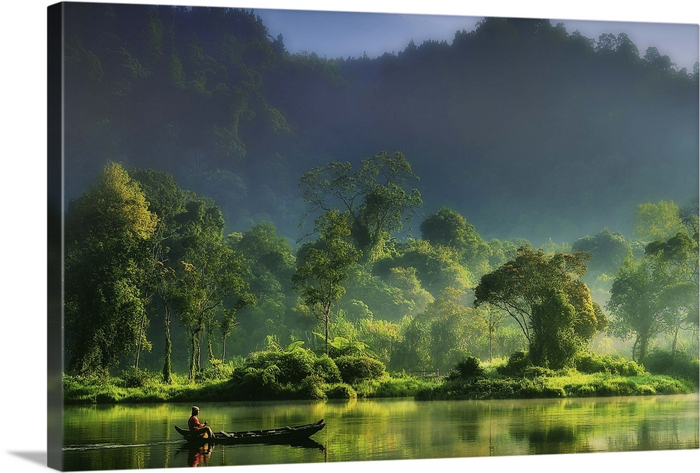 A figure on a boat in the middle of a river in the lush green Indonesian jungle.