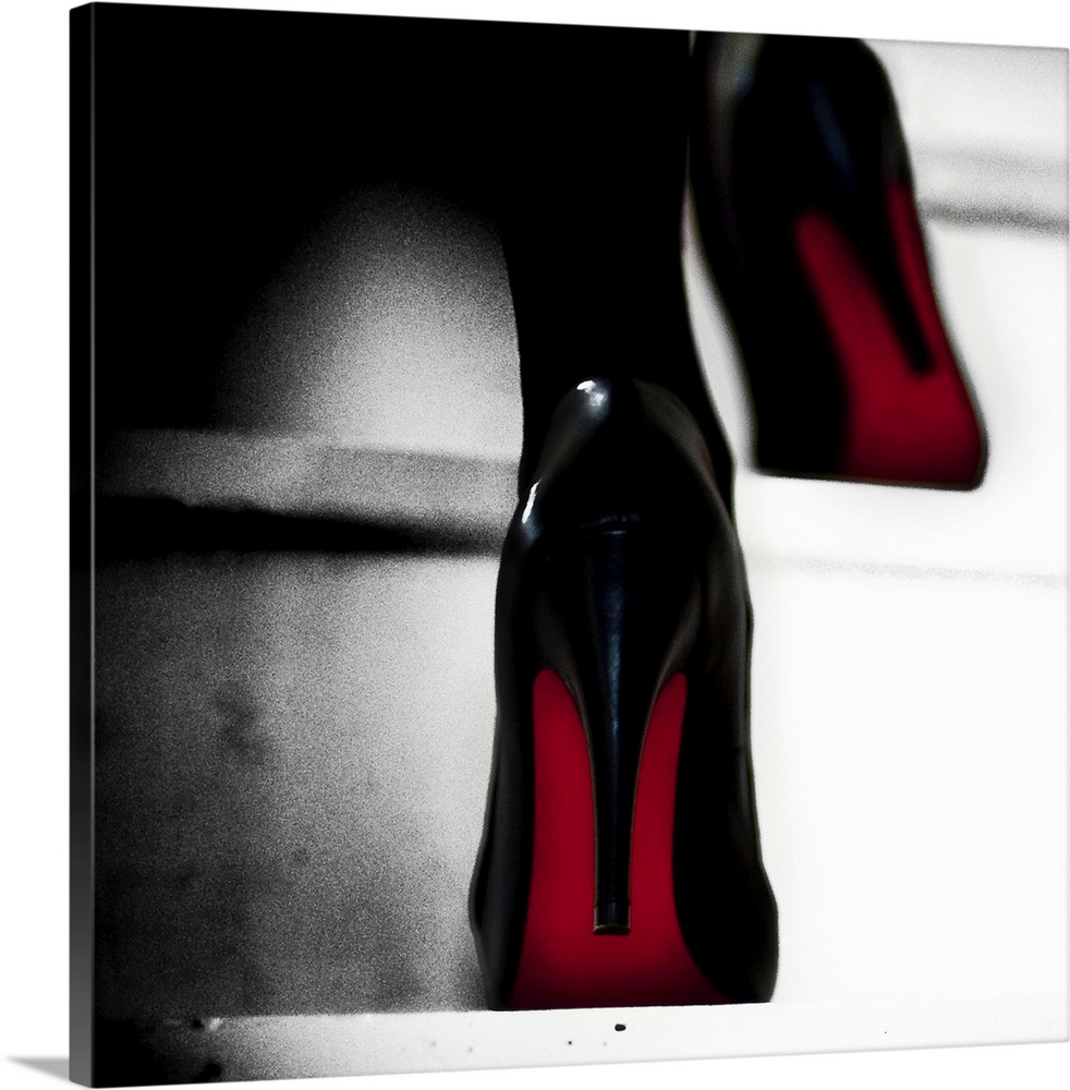 Close up view of two black high heels with red soles walking up steps.