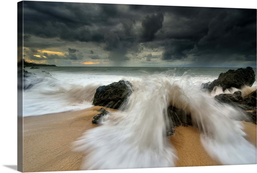 Waves crashing over a rock on Tegalwangi Beach in Bali.