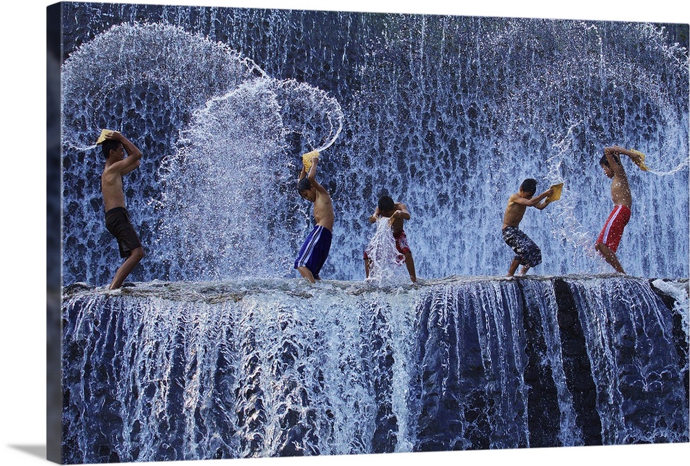 A group of children play in a waterfall, creating spiraling forms as they splash in the water.