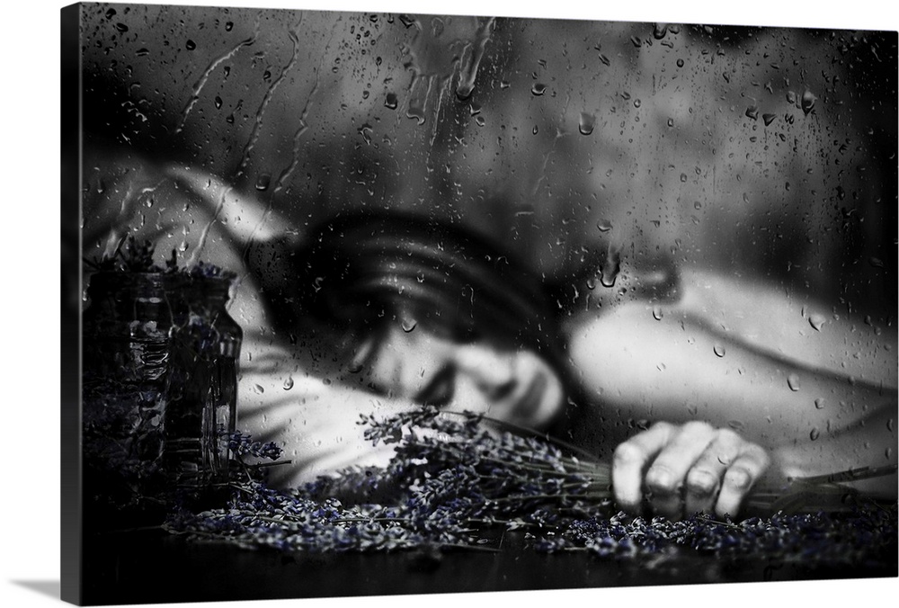 Black and white image of a woman laying down with falling raindrops.