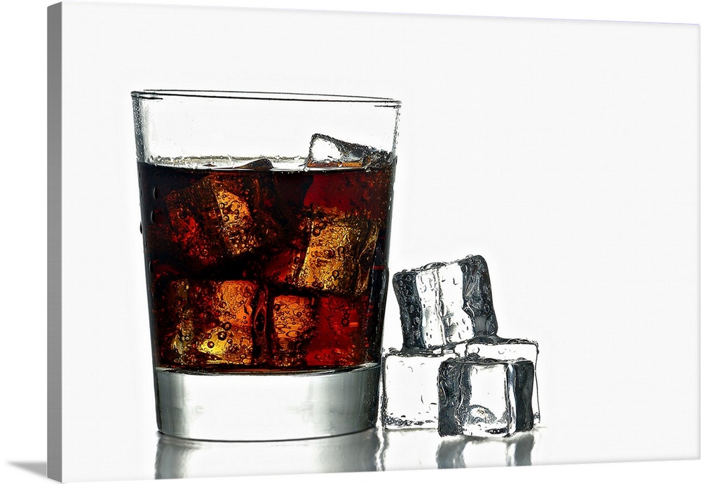 A photo of a glass of fresh icy cold cola with ice cubes next to.