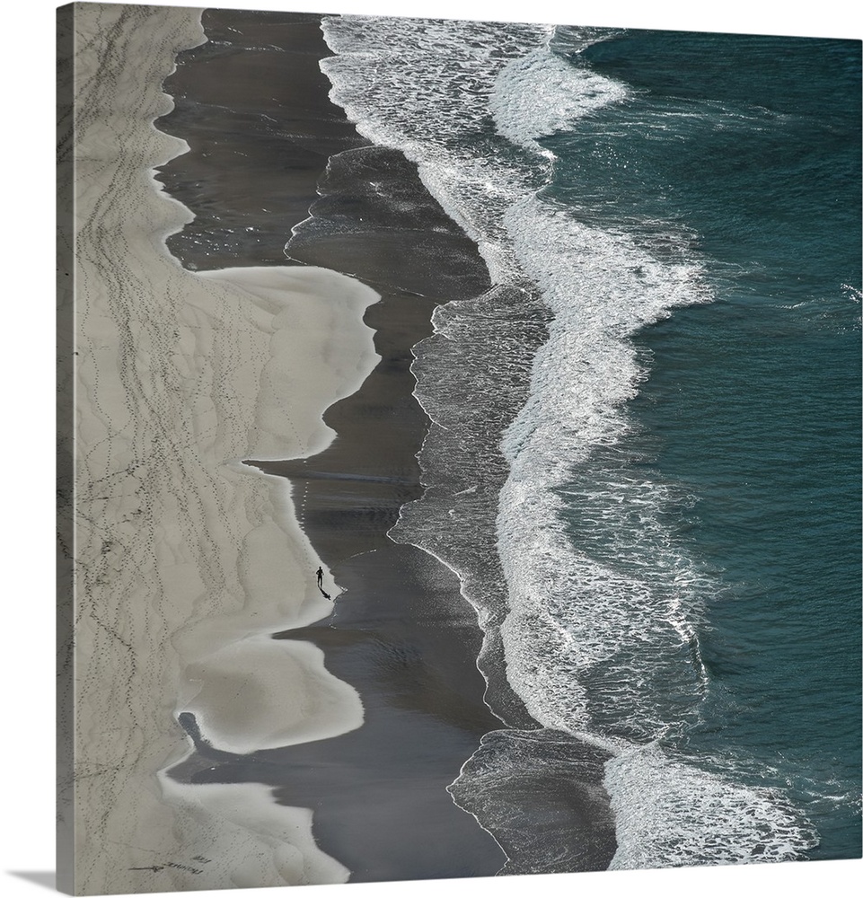 Aerial photograph of the ocean shore with tan, gray, white, and blue vertical separations.