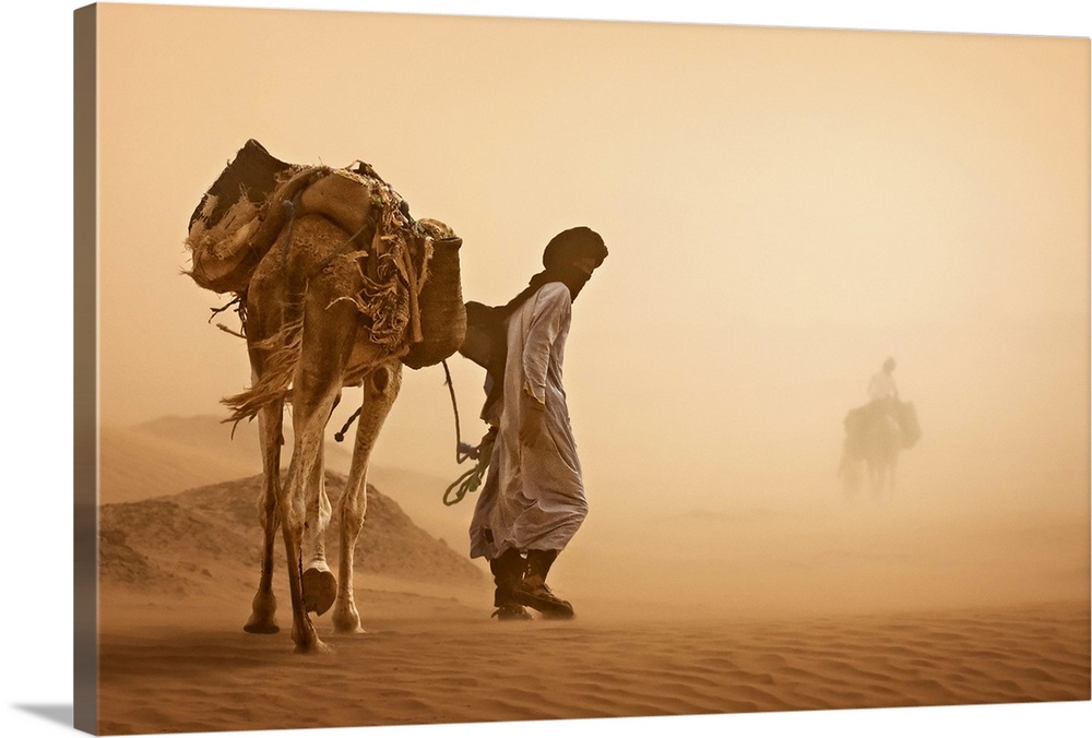 A man walks a camel carrying bags through a sandstorm in the desert in Morocco.