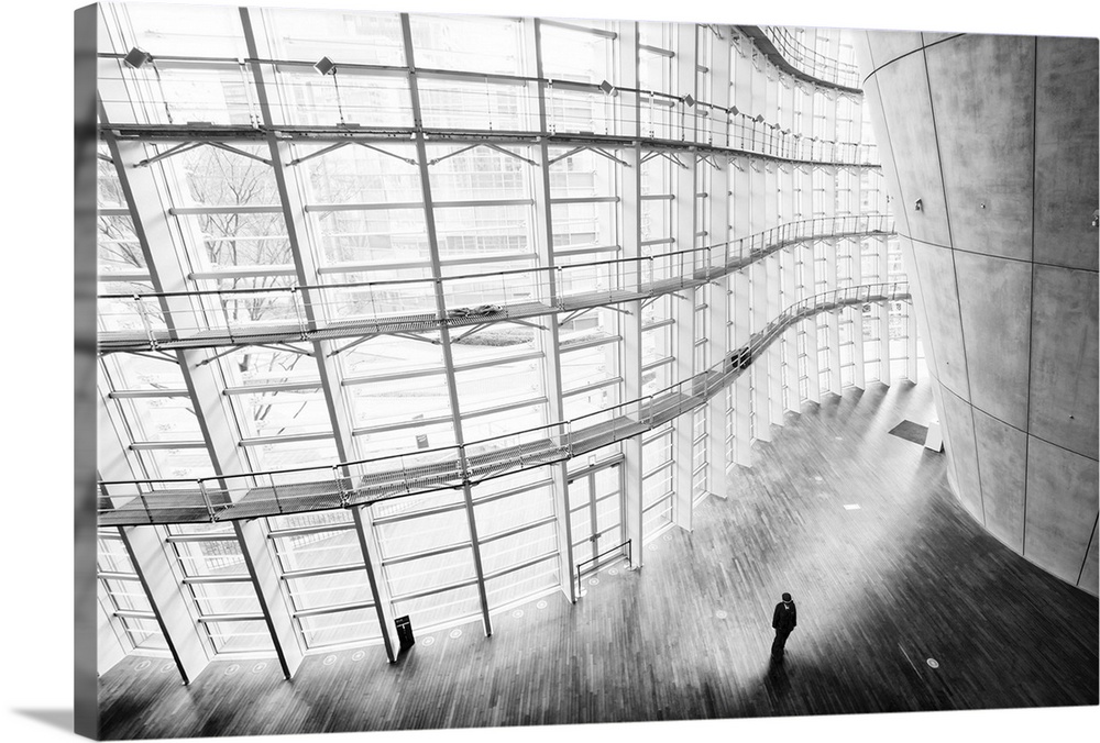 Black and white image of curving architecture, with a lone figure.