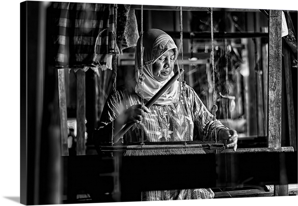 An old woman weaving away on a songket maker.