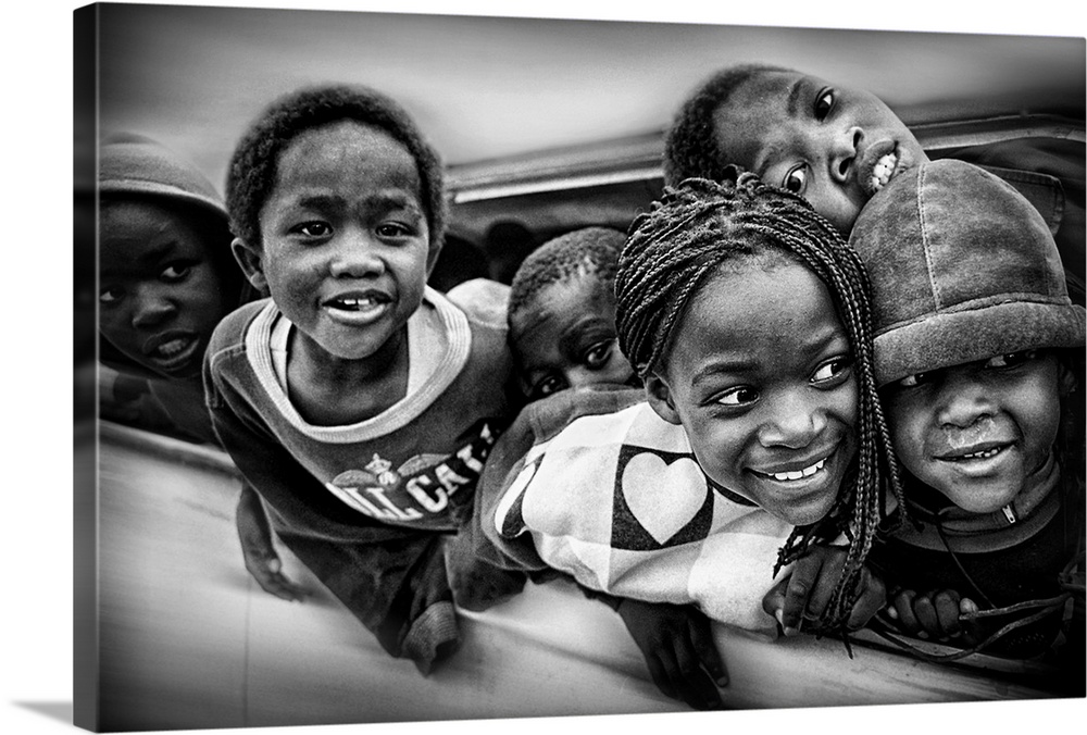 A group of young African American children lean out of the window of a car.