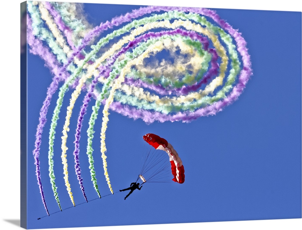 A hanglider performing tricks and spirals in the air, leaving a trail of colorful smoke.