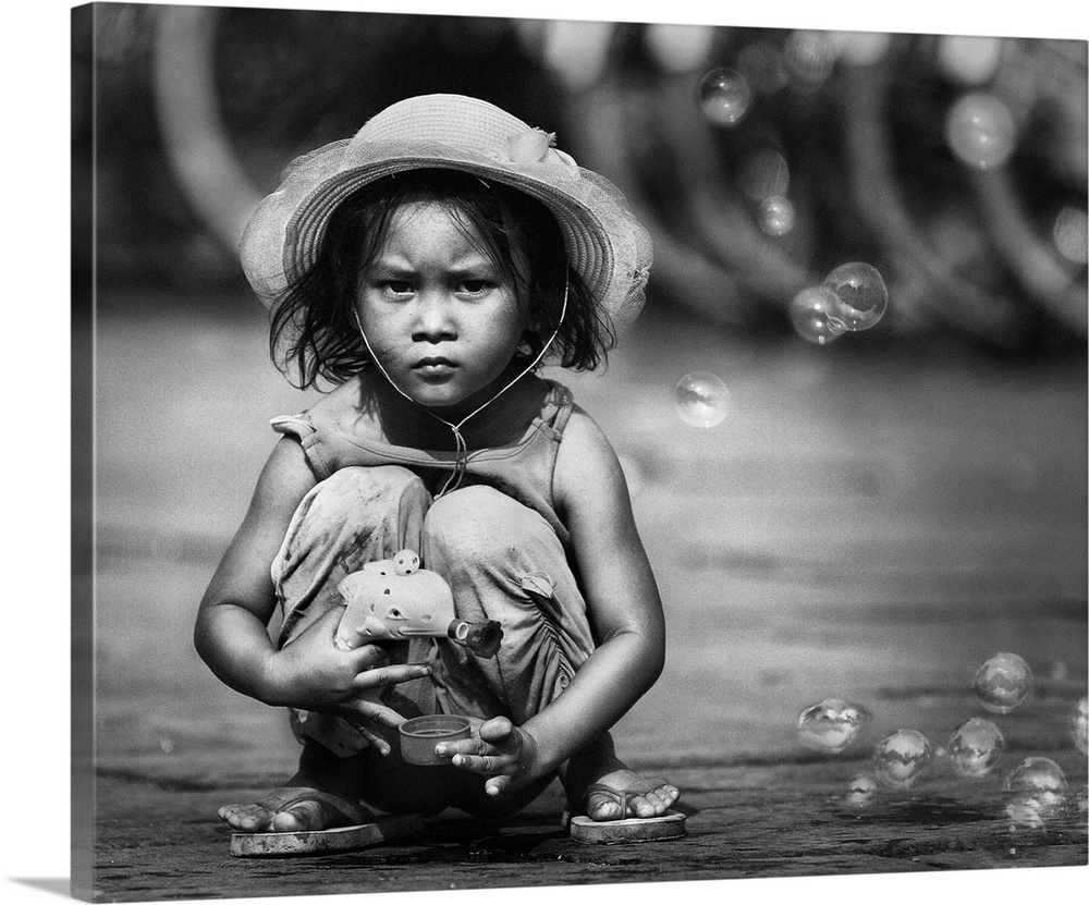 Portrait of a young Indonesian girl playing in the street with a bubble gun.