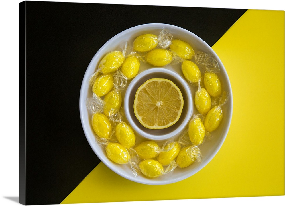 A bowl of lemon candies and a lemon slice.