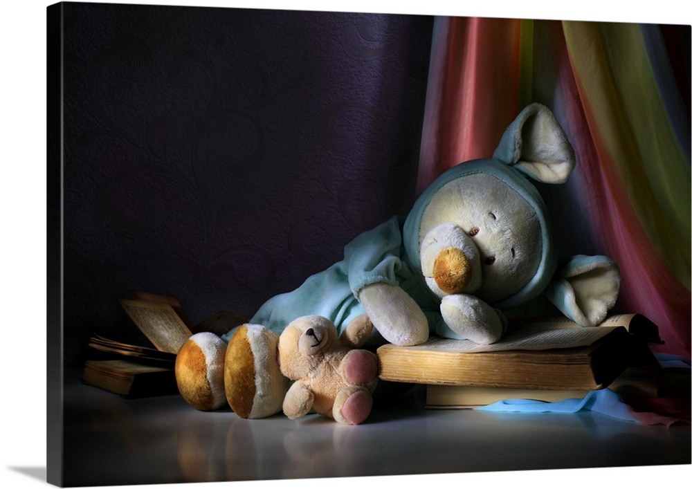 Two teddy bears appearing  to sleep on open books on a colorful curtain.