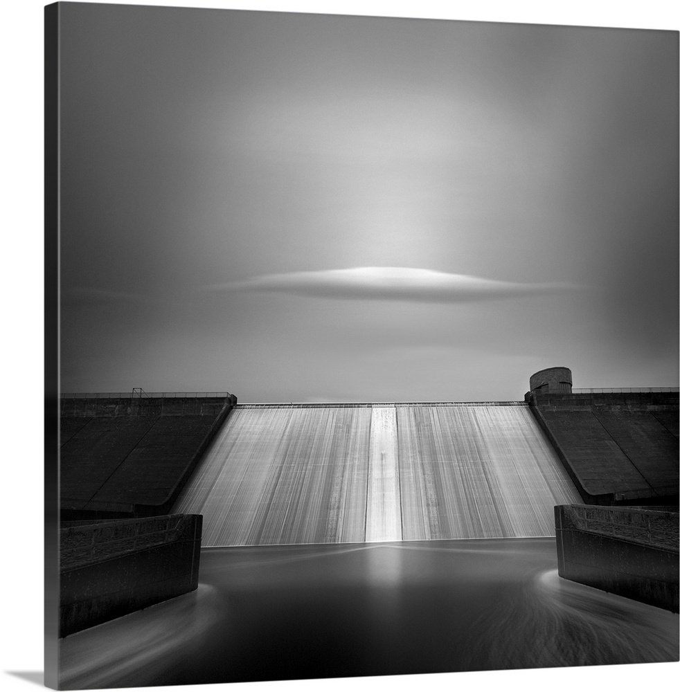 A single cloud floats above the spillway of a large dam.
