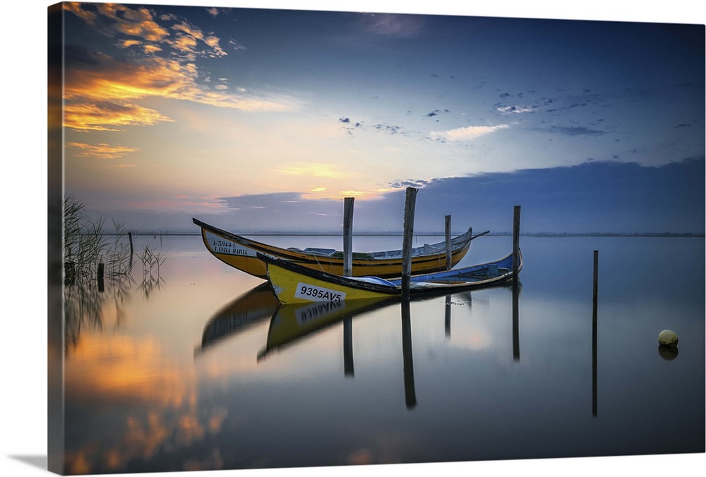 Photograph of two yellow boats docked on a calm lake at sunset.