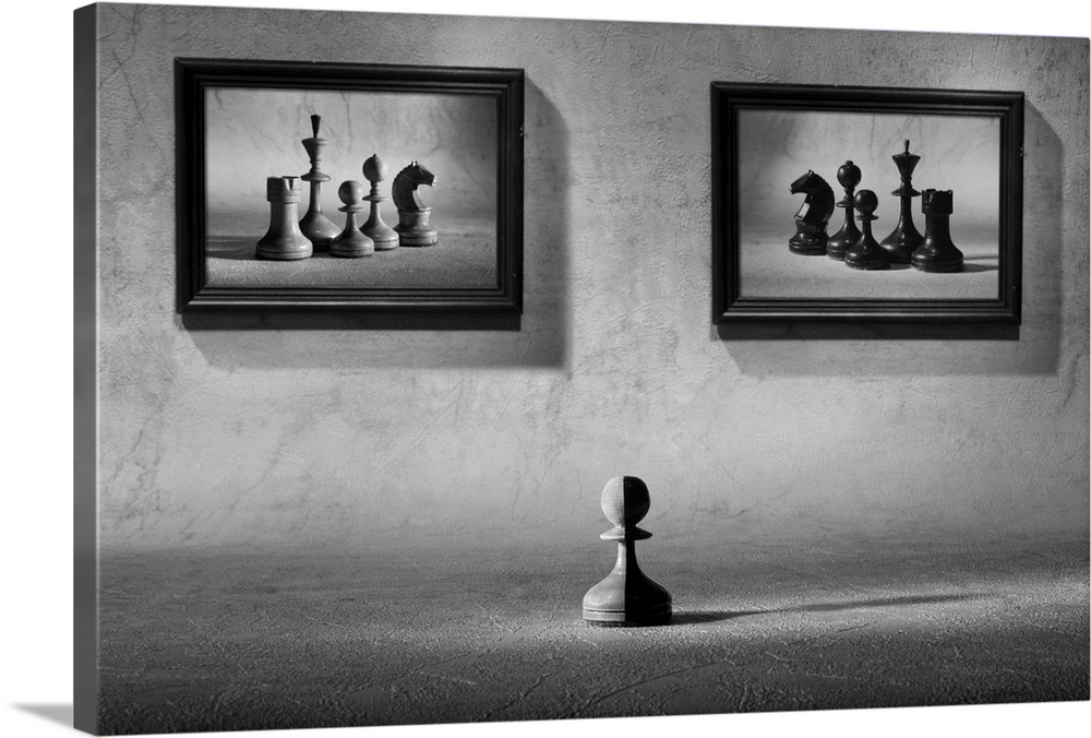 A chess pawn, half black, half white, sitting under two framed images of chess pieces of opposing sides.