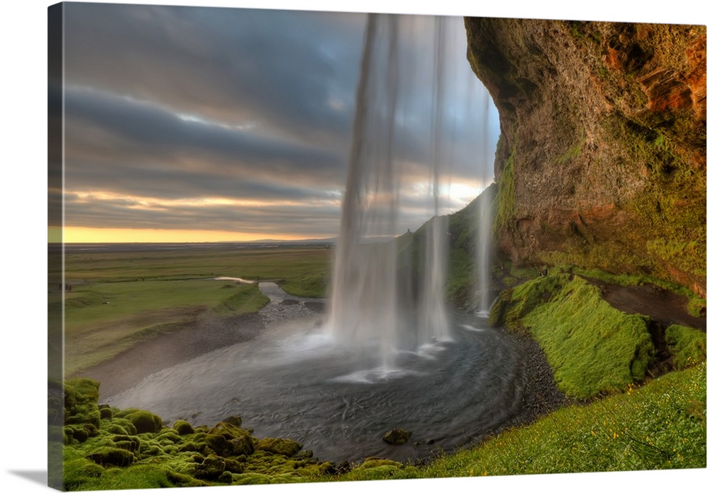 The Seljalandsfoss Waterfall in Iceland and the wide open landscape in the distance.