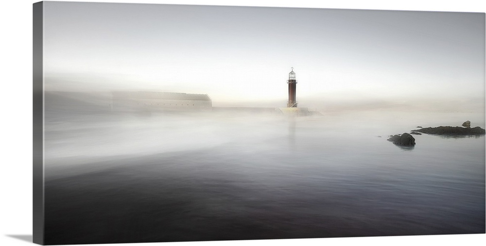 A lighthouse on a pier partially obscured by mist, making it appear as though it is rising from the ocean.